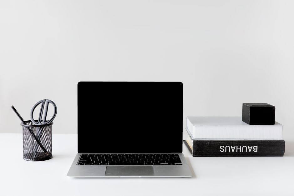 Clean and organized workspace featuring a laptop, books, and pen holder.